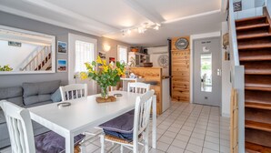 A modern kitchen with wooden cabinets, a dining table with chairs, and a staircase.
