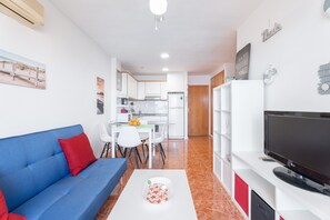 A modern living room with a blue sofa, a white coffee table, and a flat-screen TV.