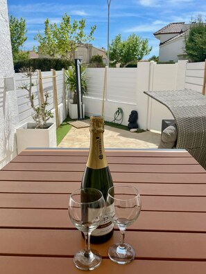 Eine Flasche Aresel Cava Wein und zwei Gläser auf einem Holztisch in einem Garten.