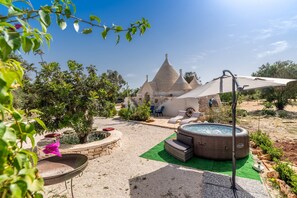 A courtyard with a hot tub, outdoor seating, and a stone building with conical roofs.