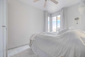A bedroom with a bed, a ceiling fan, a window with curtains, and a chandelier. - Apartment 'Sea View Paradize' with Sea View, Wi-Fi and Air Conditioning (Fuengirola)