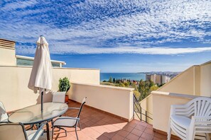 A balcony with a table and chairs, a potted plant, and a view of the sea and cityscape. - Apartment 'Sea View Paradize' with Sea View, Wi-Fi and Air Conditioning (Fuengirola)