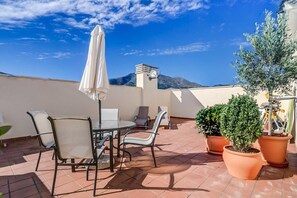 A terrace with a table and chairs, potted plants, and a view of the mountains. - Apartment 'Sea View Paradize' with Sea View, Wi-Fi and Air Conditioning (Fuengirola)