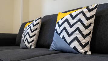 A dark-colored sofa with two patterned pillows, one with a zigzag design and another with a yellow top.