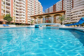Une piscine avec un pont, entourée d’immeubles à plusieurs étages.