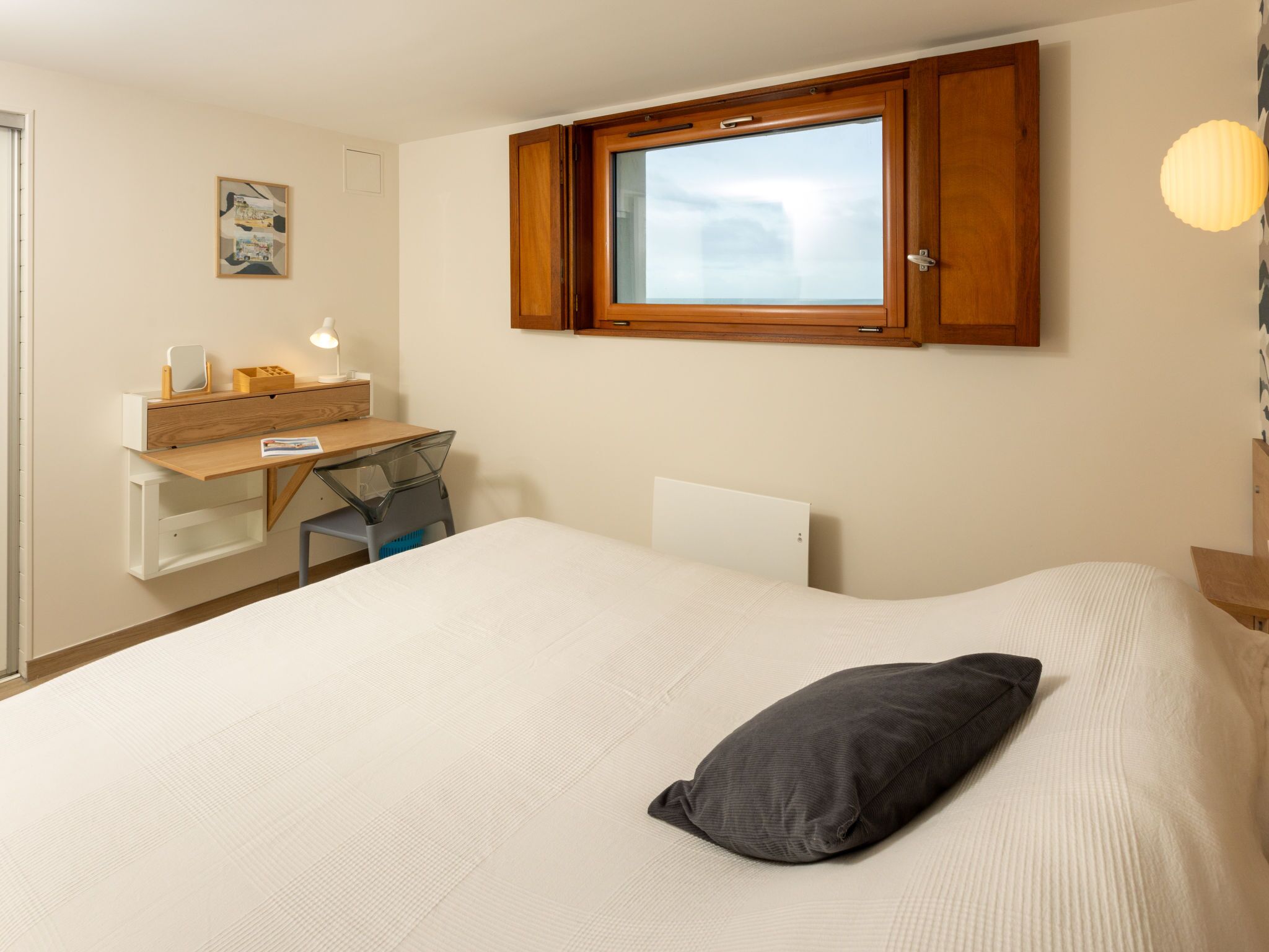 Ein Schlafzimmer mit einem Bett, einem Schreibtisch und einem Fenster.