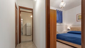 A bedroom with a bed, a nightstand, a wall-mounted lamp, and a door leading to a bathroom.