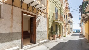 A narrow street with buildings, a visible door, and a vehicle in the distance.