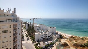 A coastal hotel with multiple floors, a beach view, and a pier in the background.