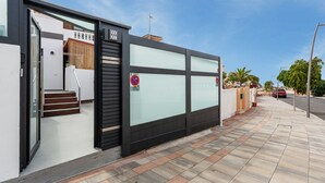 Un edificio moderno con fachada de vidrio, una puerta metálica y cielo despejado.