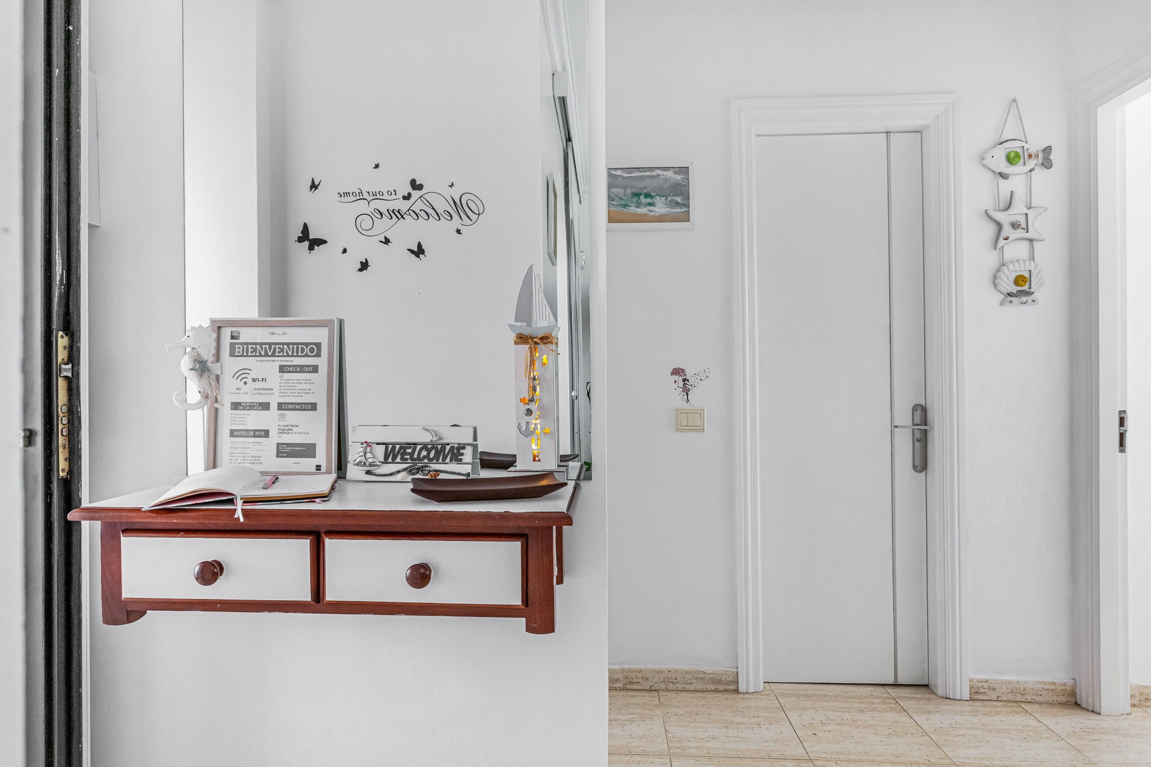 Un comptoir d’accueil avec une pancarte de bienvenue, un tableau encadré et un élément décoratif mural.
