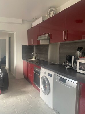 A compact kitchen with a washing machine, a coffee maker, and a microwave.