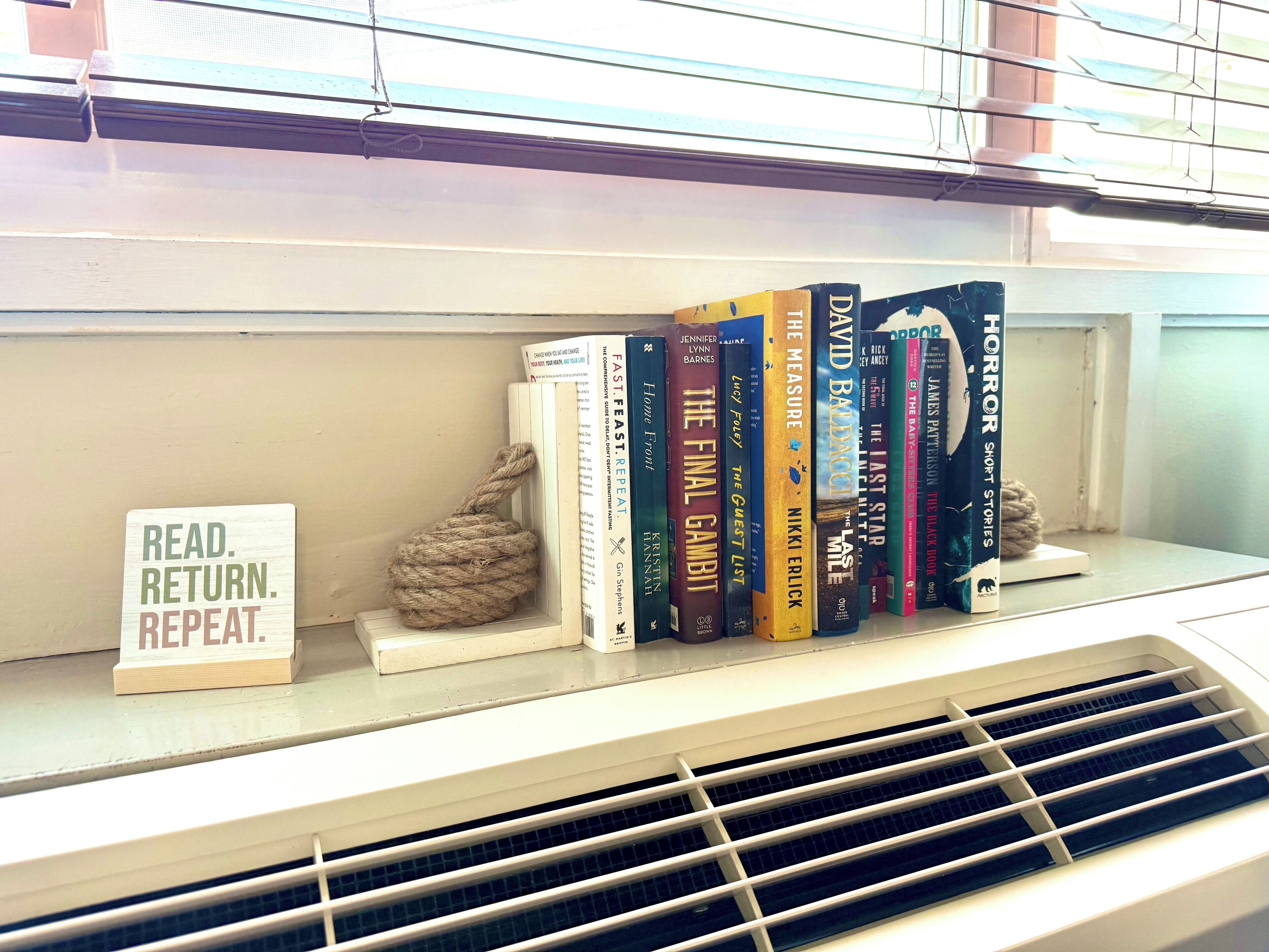 Una estantería con libros y un cartel que dice "LEER. DEVOLVER. REPETIR".
