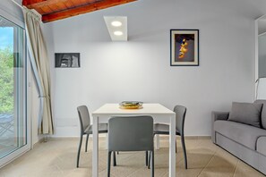 Une pièce comprenant une table à manger, des chaises, un canapé, un luminaire au plafond et un tableau encadré accroché au mur.