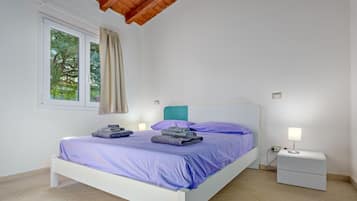 A bedroom with a bed, a nightstand, a lamp, and a window with curtains.