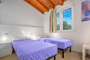 Habitación con dos camas, una ventana con cortinas, techo de madera y un cuadro colgado en la pared.