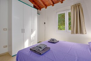 Une chambre à coucher avec un lit, une armoire, une fenêtre et un rideau.