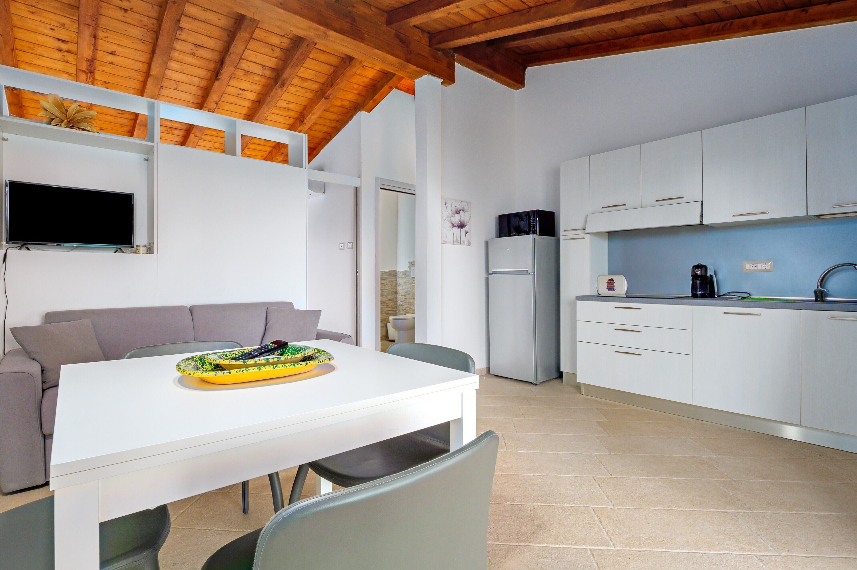 A modern kitchen with white cabinets, a built-in microwave, and a coffee maker.