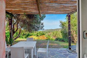 Un patio al aire libre con mesa y sillas, una pérgola y vistas a un paisaje natural.