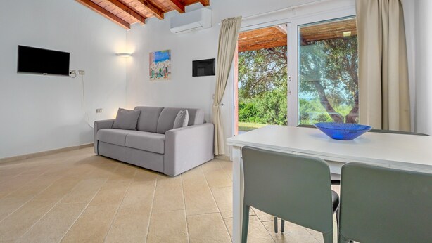 Una sala de estar con un sofá, una mesa con un tazón, un televisor y una ventana con cortinas.