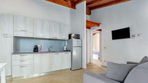 Una cocina moderna con armarios blancos, un refrigerador, un microondas y una cafetera.