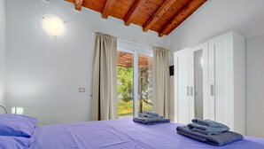 Un dormitorio con cama, armario y ventana con cortinas.
