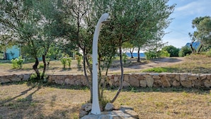 Un jardín con una escultura blanca, un muro de piedra y árboles.
