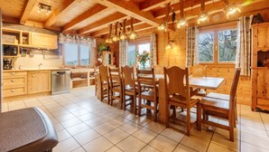 Ein Holzblockhaus-Interieur mit Küche, Essbereich und großen Fenstern.