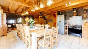 Ein Holzinterieur mit einem Esstisch, Stühlen, einer Küche mit Herd und Kühlschrank.