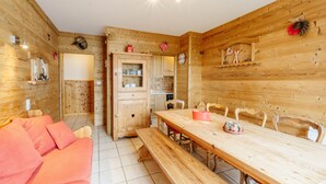 Un intérieur en bois comprenant une table à manger, des bancs, un canapé et un coin cuisine.