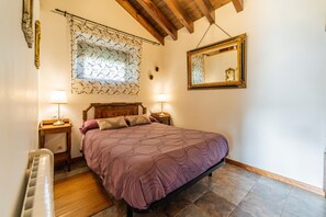 A bedroom with a bed, two bedside tables with lamps, a wooden headboard, a window with curtains, a mirror, and a radiator. - Country House 'Villamoronta' with Mountain View, Private Terrace and Wi-Fi (La Rad)