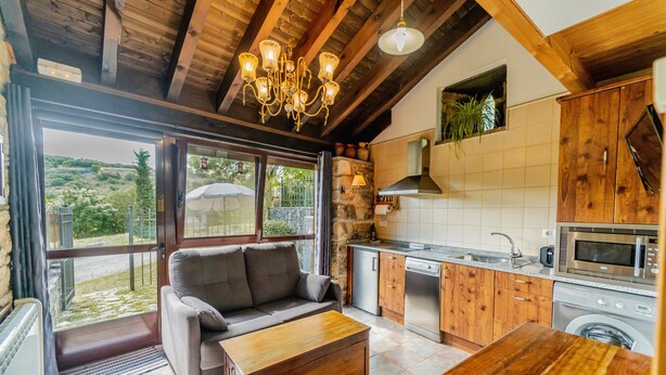 Eine gemütliche Küche mit Holzschränken, einem eingebauten Ofen und einem Essbereich mit Holztisch und Sofa.