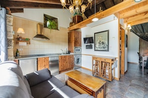 A modern kitchen with wooden cabinets, a built-in oven, and a dining area with a wooden table and bar stools. - Country House 'Villamoronta' with Mountain View, Private Terrace and Wi-Fi (La Rad)