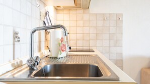 A kitchen with a stainless steel sink, a faucet, and a white countertop.