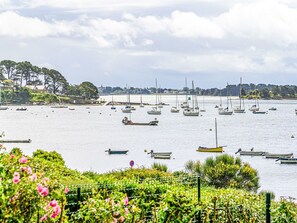 A marina with various boats docked, surrounded by greenery and a distant shoreline with buildings. - Maison La Prâme by Interhome (Arradon)