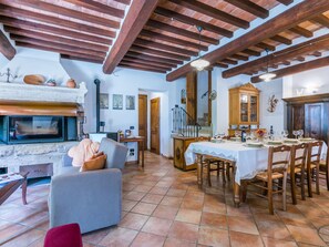 A spacious dining area with a wooden table set for a meal, a fireplace, and a view of the kitchen.