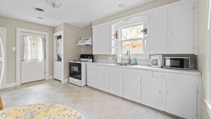 A modern kitchen with white cabinets, a microwave, a stove, and a sink.