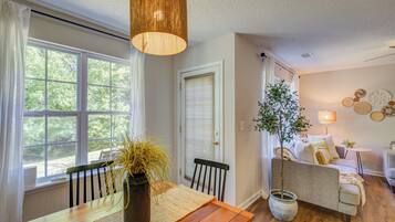 A room with a dining table, chairs, a sofa, a lamp, and a plant.