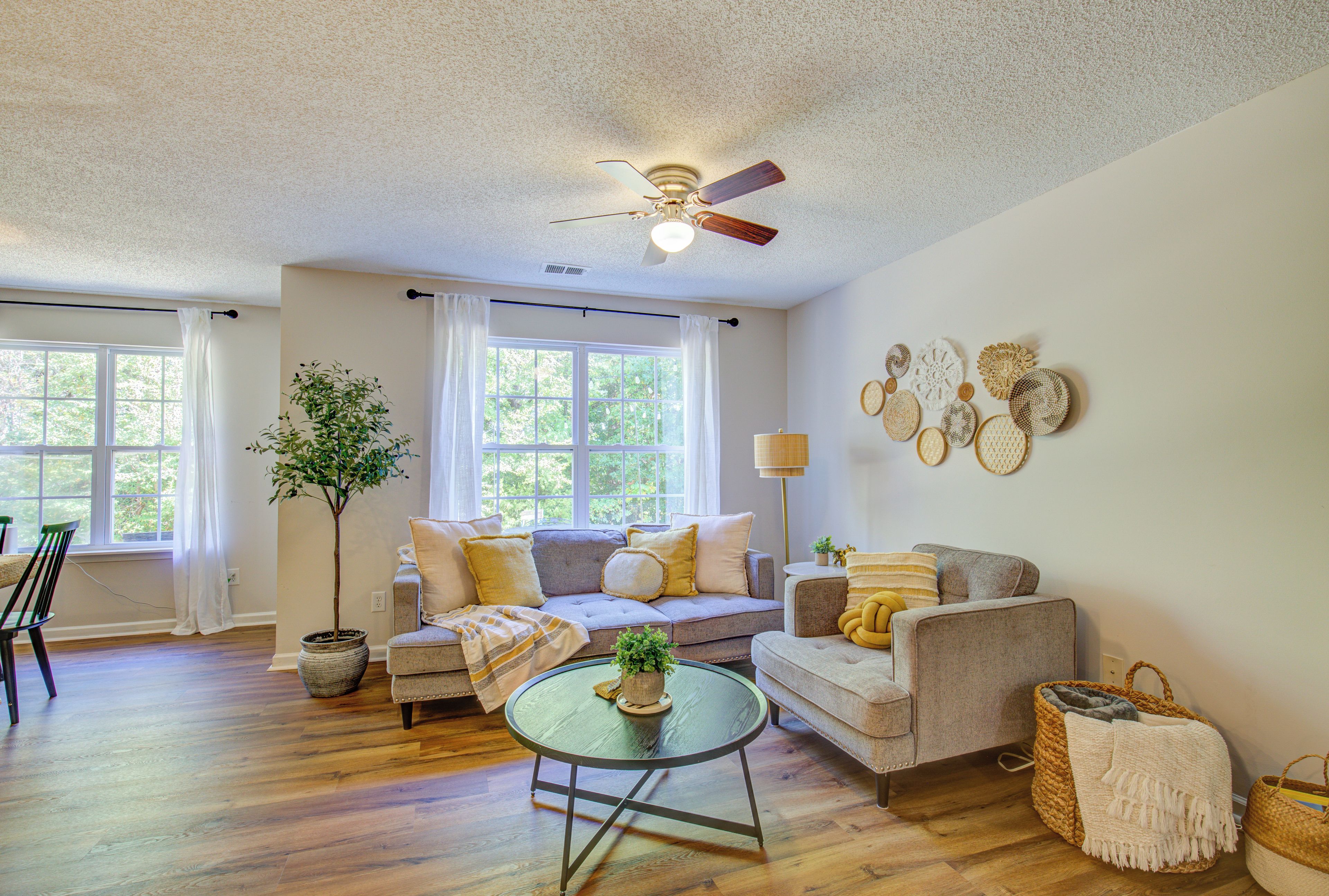 A living room with a ceiling fan, two sofas, a coffee table, and a potted plant.