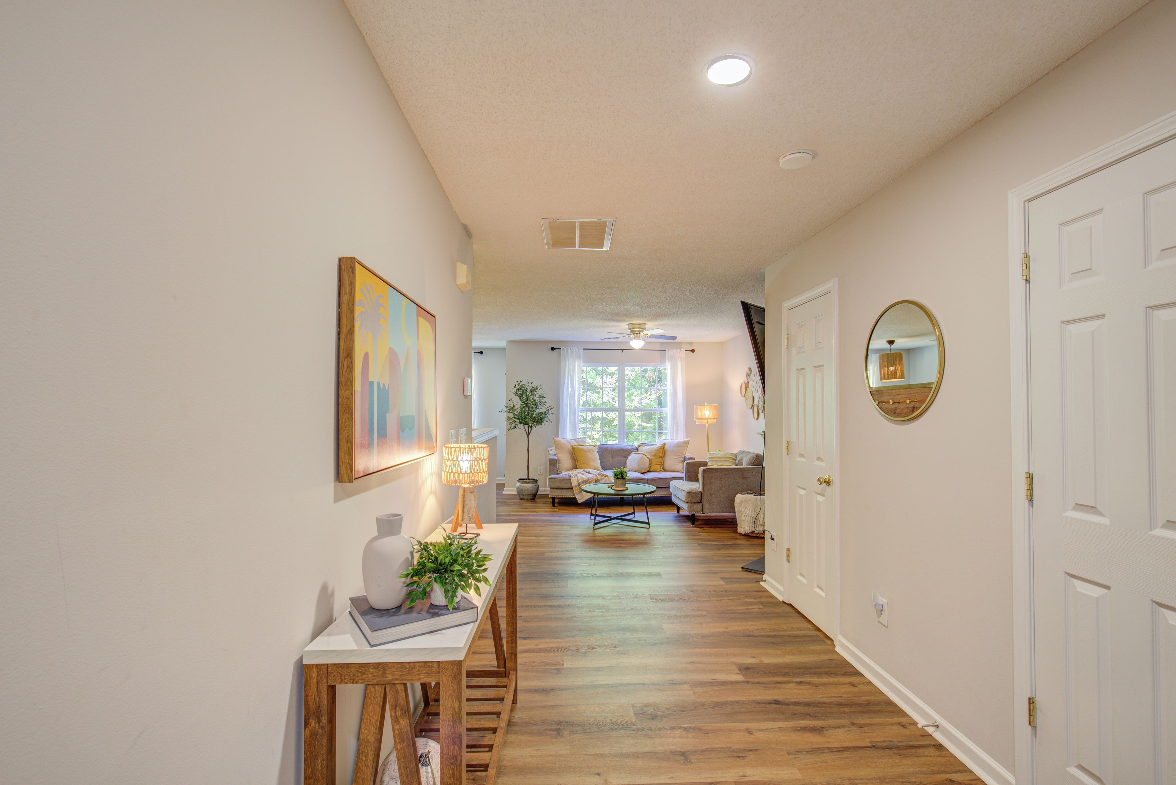 A hallway with a wooden floor, a white door, and a ceiling fan.