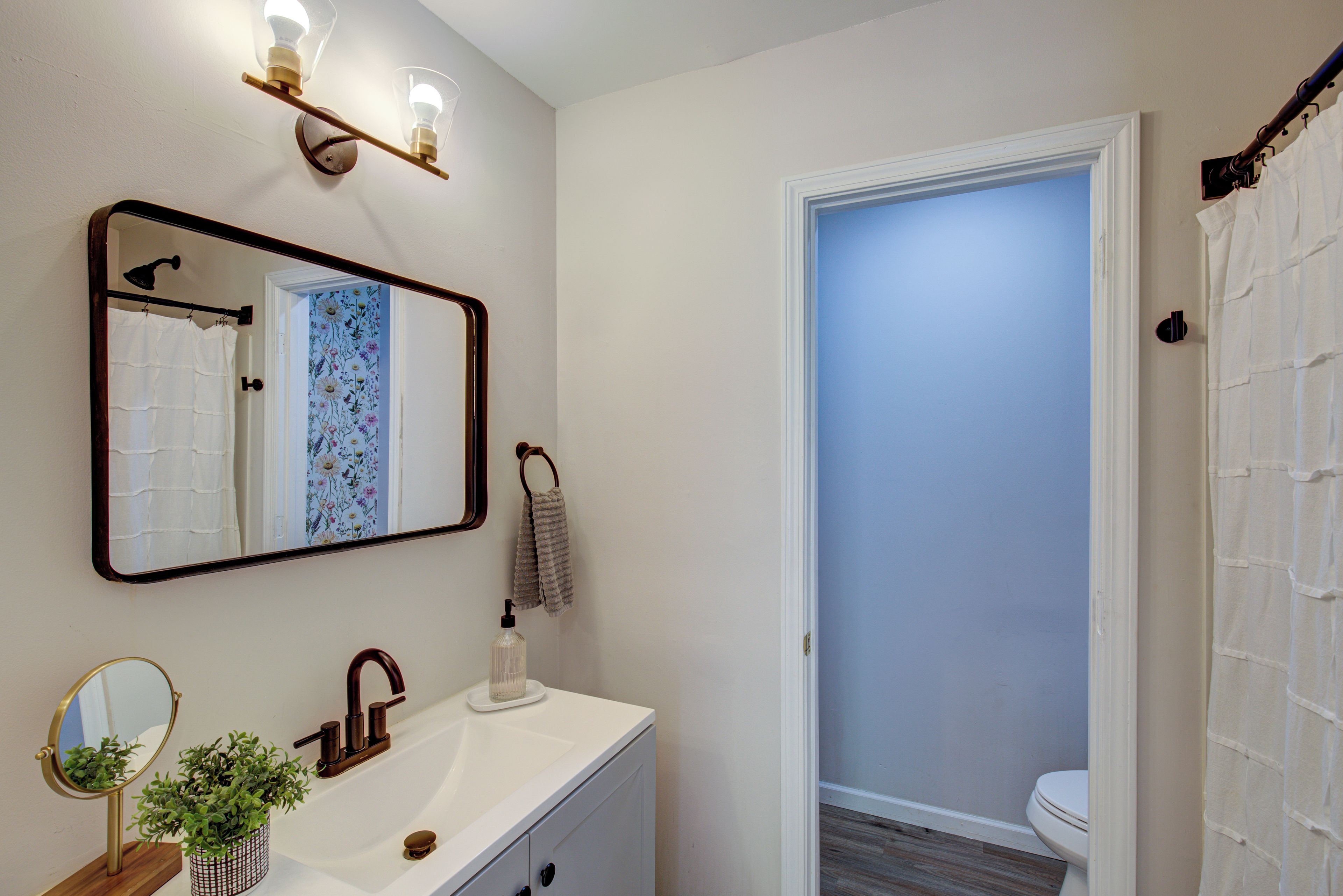A bathroom with a white sink, a mirror, a towel rack, and a shower curtain.