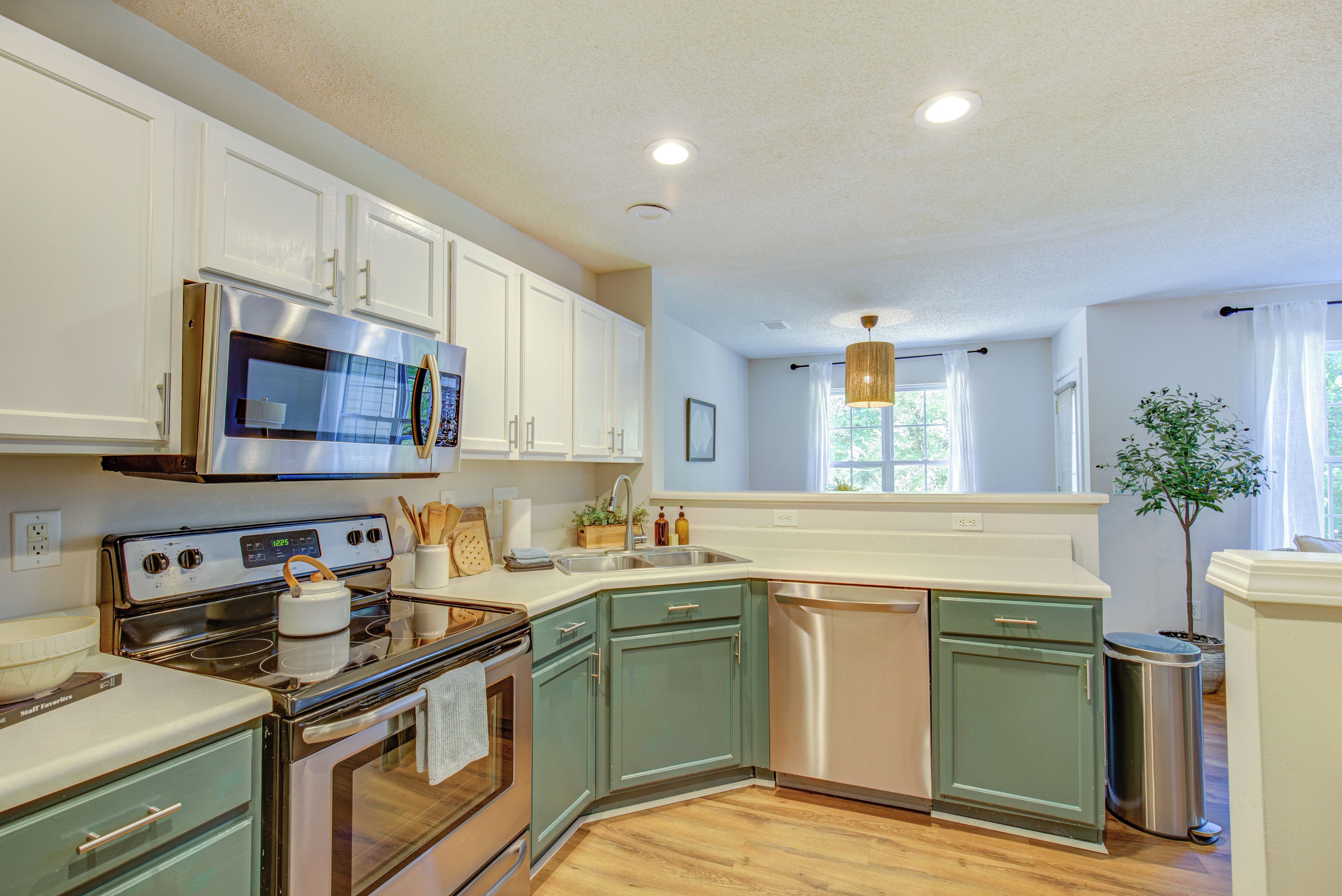 A kitchen with white cabinets, stainless steel appliances, and a wooden floor.