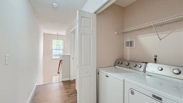 A laundry room with a washing machine and dryer, a window with blinds, and a ceiling vent.