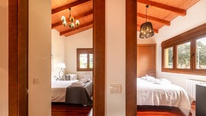 A bedroom with wooden flooring, two beds, a ceiling fan, and large windows. - Villa Sonrisa de Llanes (Pancar)