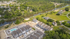 Vista aérea de una zona residencial con casas, un río y una piscina.