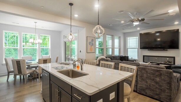Una cocina moderna con una isla grande, comedor y sala de estar con un televisor grande.