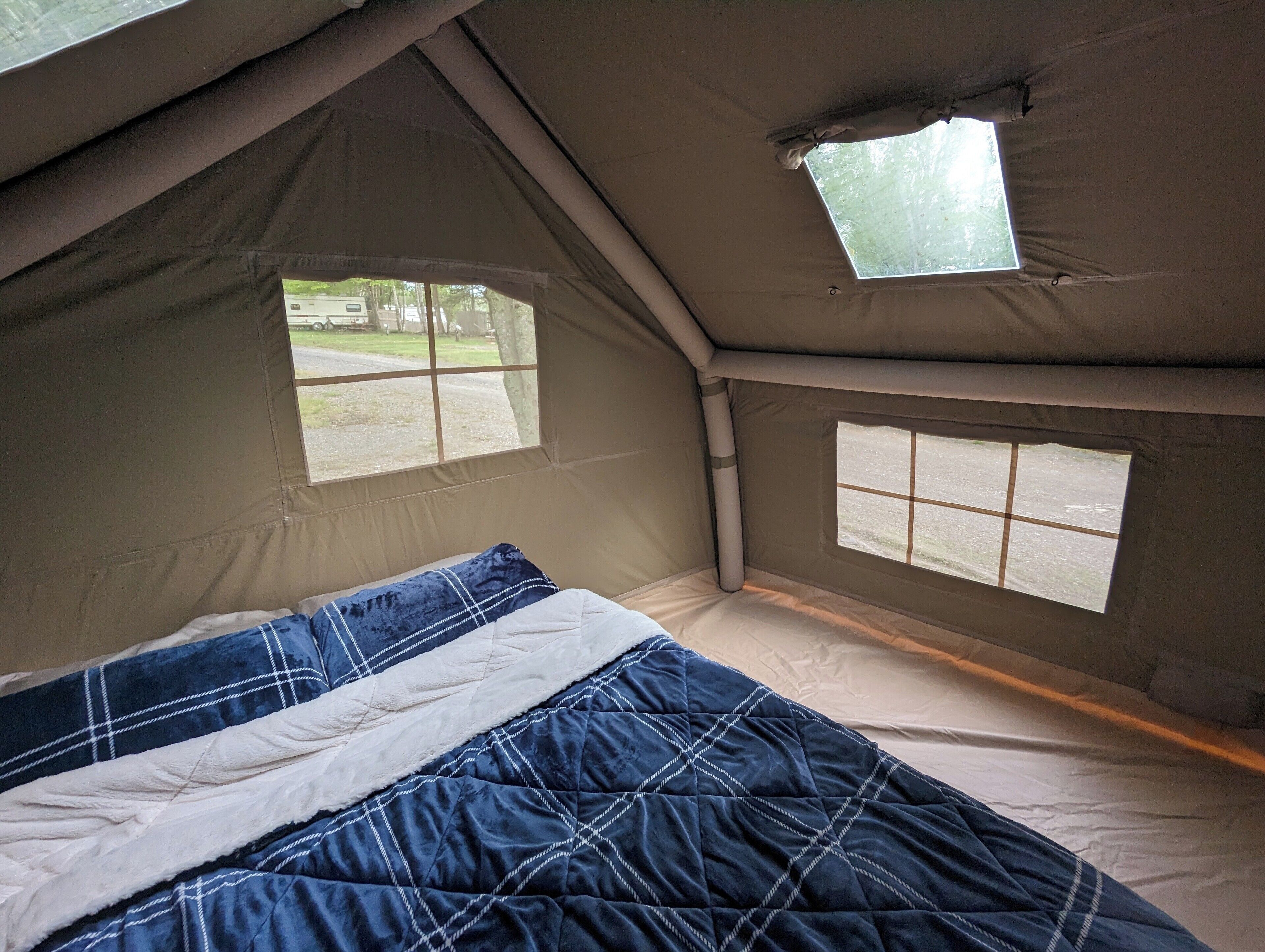 Ein Zelt mit Bett, zwei Fenstern und Blick ins Freie.