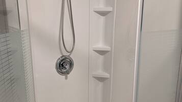 Een douche met glazen wand, een handdouche en een kraan op de muur.