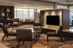 A hotel lobby with a seating area, a flat-screen TV, and a decorative wall. - King Studio Near Atek Pest Control Inc MIA (Miami)