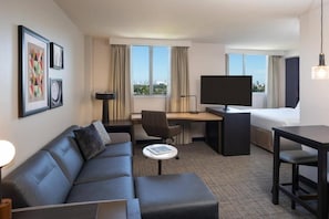 A hotel room with a sofa, a desk, a bed, and a TV. - King Studio Near Atek Pest Control Inc MIA (Miami)